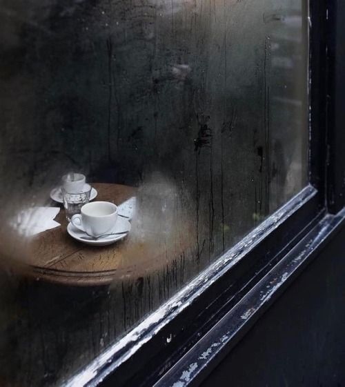 a cup and saucer sitting on top of a wooden table next to a window