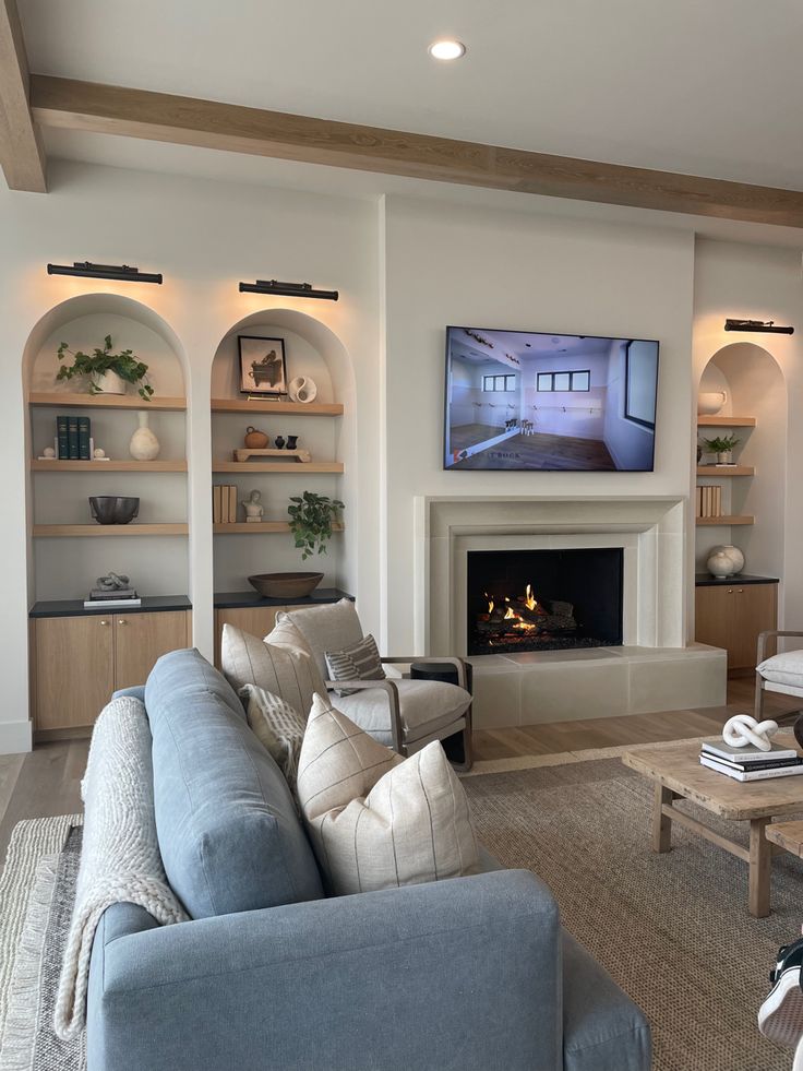 a living room filled with furniture and a flat screen tv mounted on the wall above a fire place