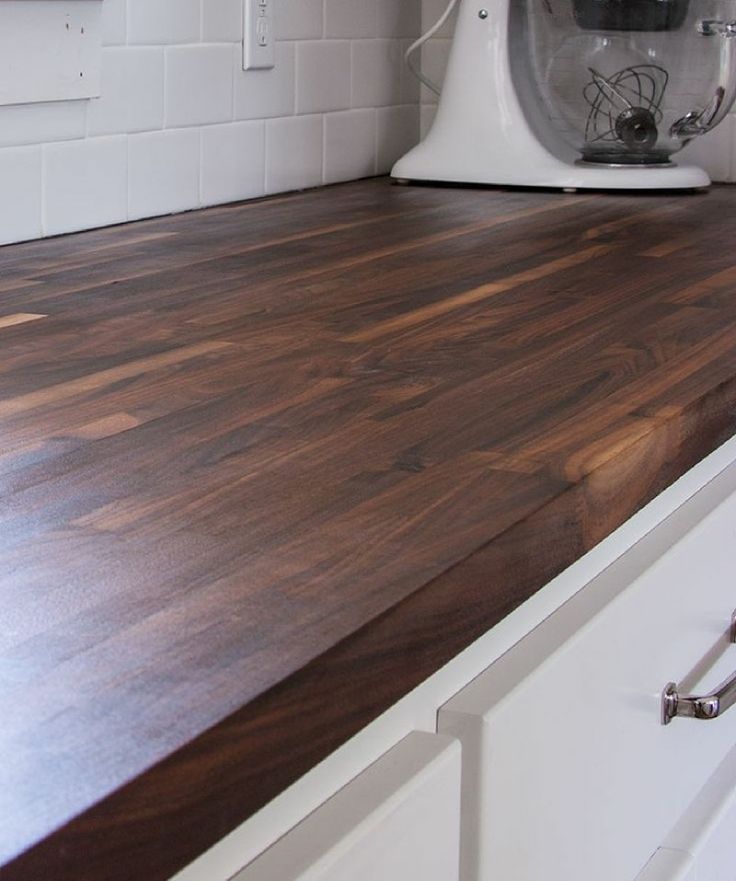 a kitchen counter top with a mixer on the wall in the back ground and white cabinets to the side