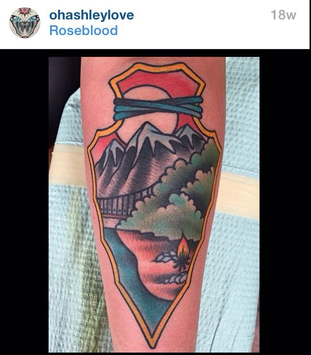 a person with a tattoo on their leg that has mountains and trees in the background