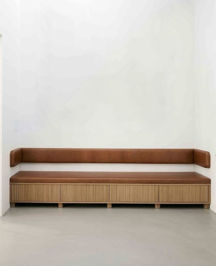 an empty room with a wooden bench and white walls