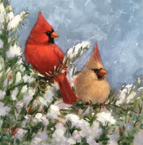 two red birds sitting on top of snow covered branches