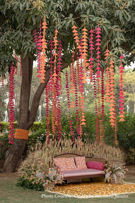 a couch under a tree with flowers hanging from it