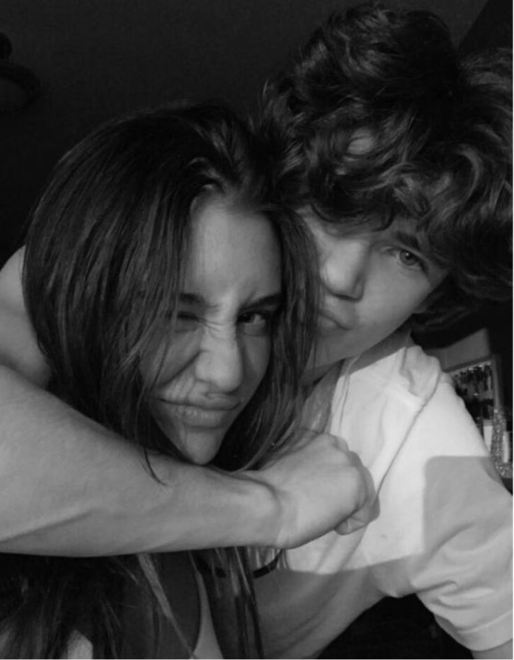 two young women hugging each other in the middle of a room with dark lighting behind them