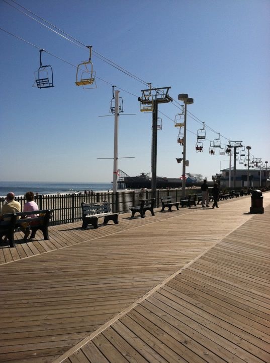 people are sitting on benches near the water and some power lines in the sky above them