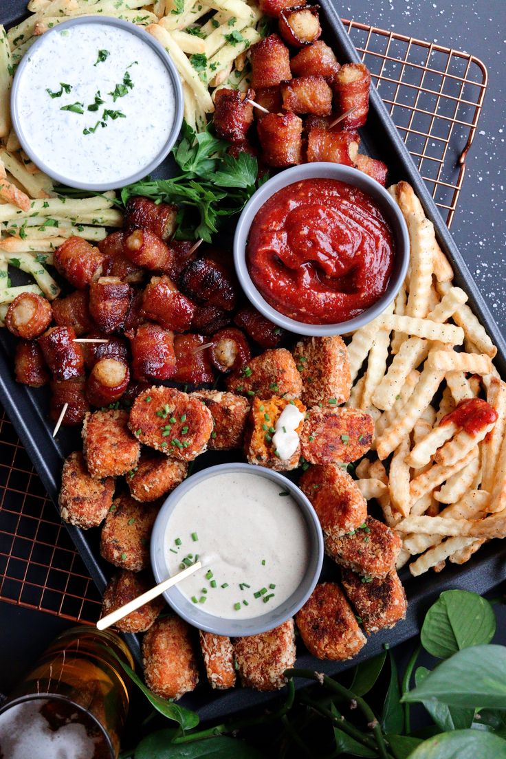 a platter filled with different types of food and dipping sauces on top of it