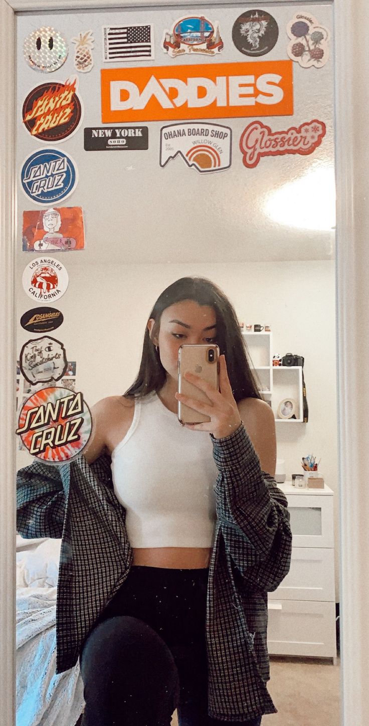 a woman taking a selfie in front of a mirror with stickers on it