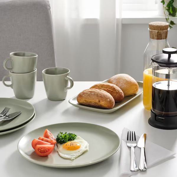 a table set for breakfast with eggs, tomatoes and bread on the plate next to an orange juicer