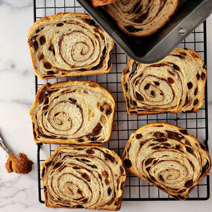 four pieces of cinnamon swirl bread on a cooling rack next to a loaf of bread