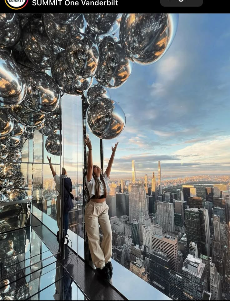 a man standing on top of a tall building with lots of shiny balls hanging from the ceiling