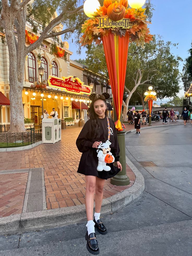 a woman is holding a stuffed animal in front of a street sign that says disneyland