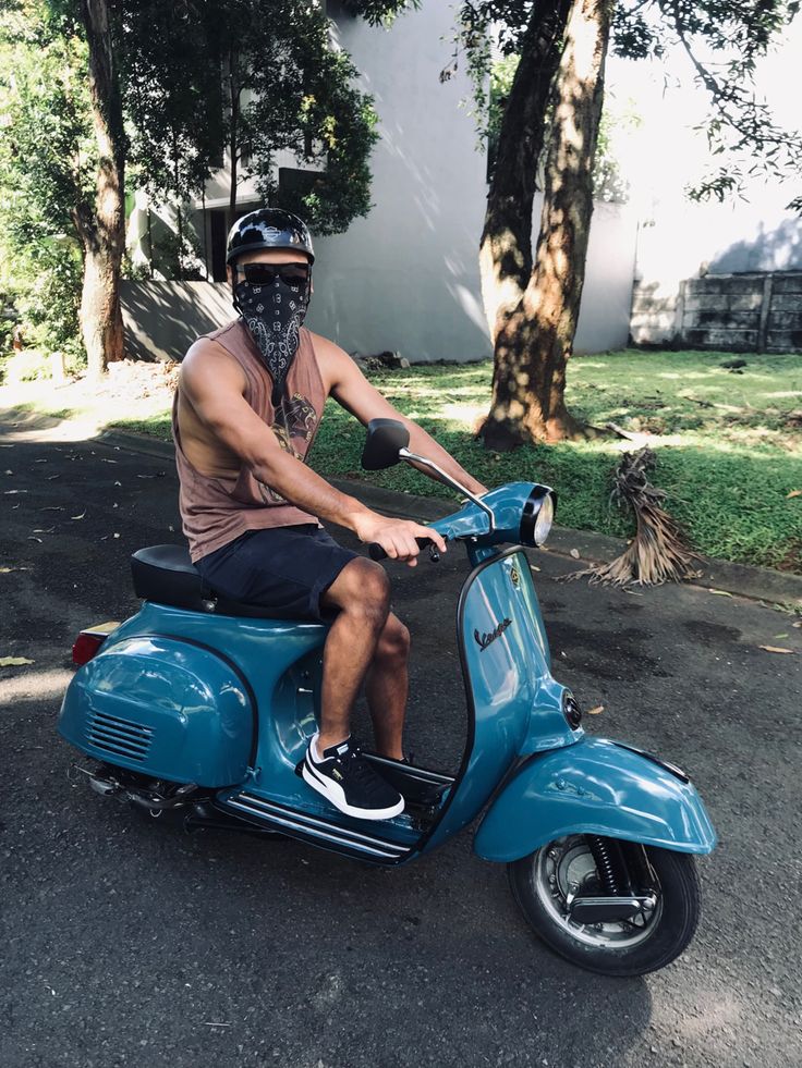 a man riding on the back of a blue scooter