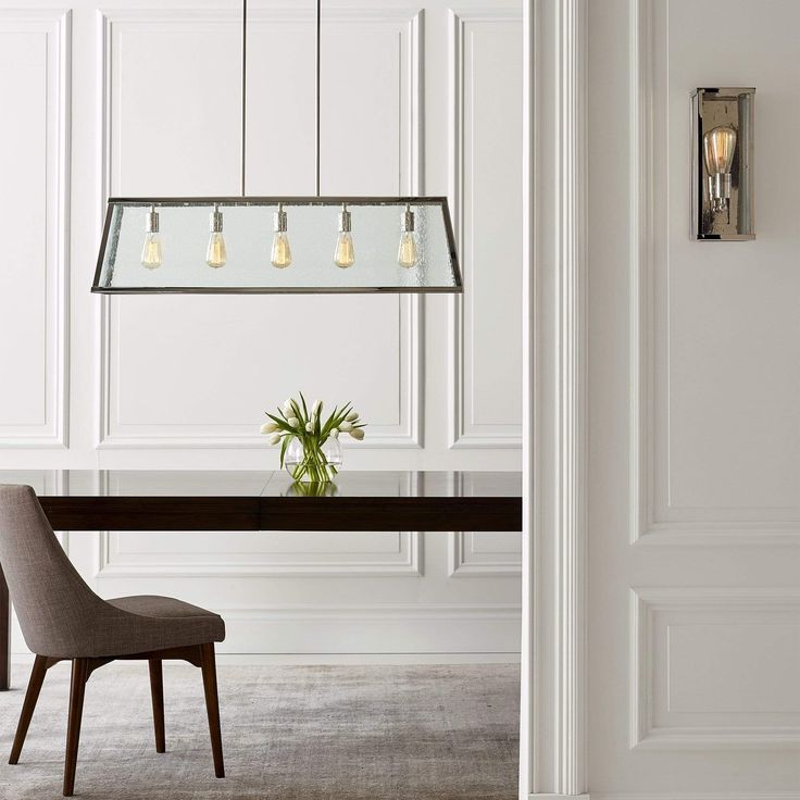 a dining room with a table, chairs and chandelier hanging from the ceiling