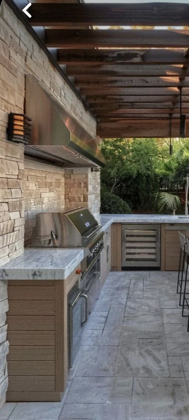 an outdoor kitchen with bar stools and grill