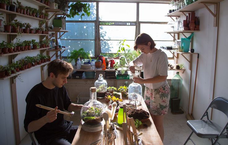 two people sitting at a table with plants