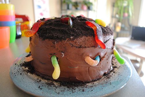 a chocolate cake with worms on it sitting on a plate