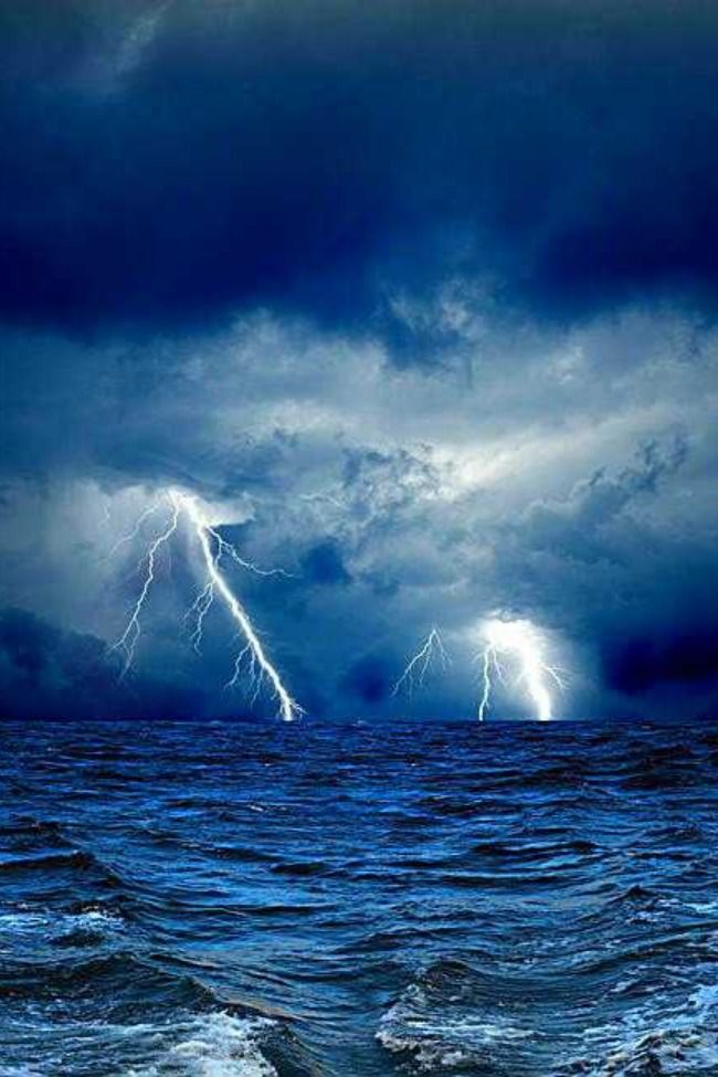 two lightning strikes over the ocean on a stormy day with dark clouds and blue water