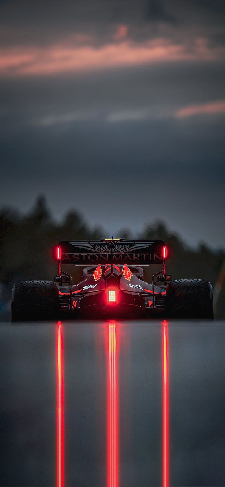 a race car with its lights on driving down the track