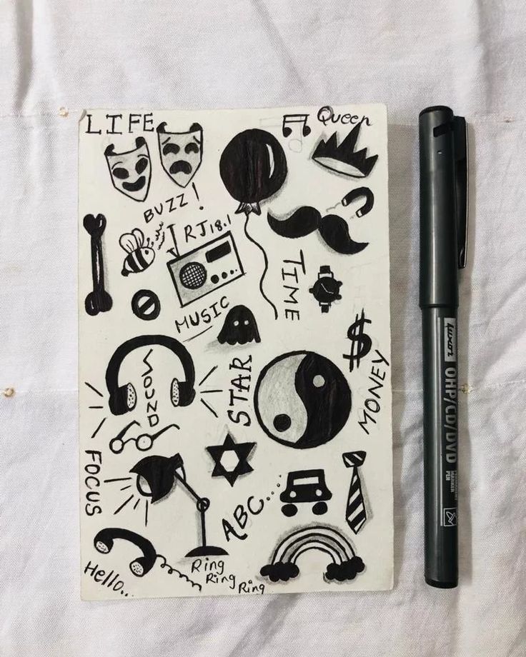 a notebook covered in black and white doodles next to a pen on top of a sheet of paper