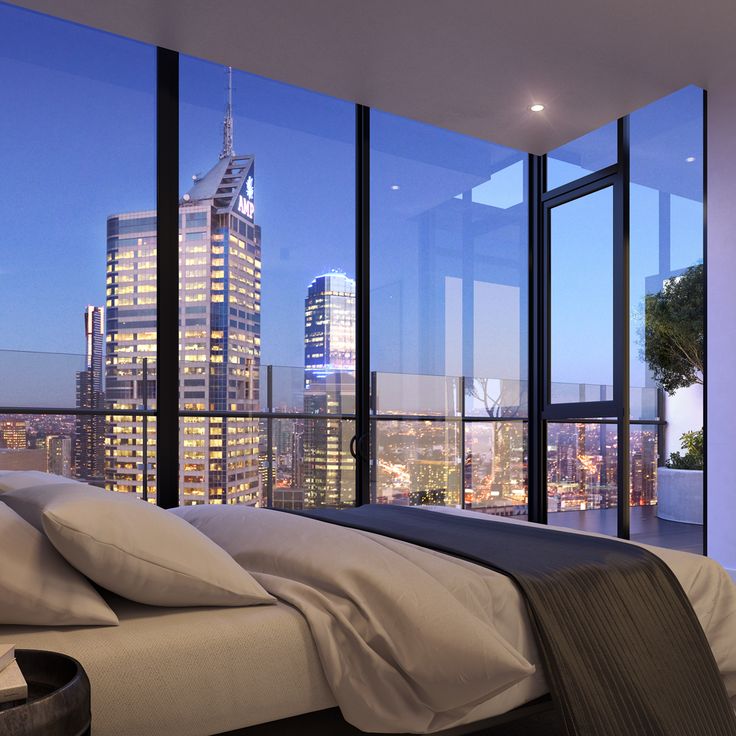 a bedroom with a large window overlooking the city at night, and a view of skyscrapers