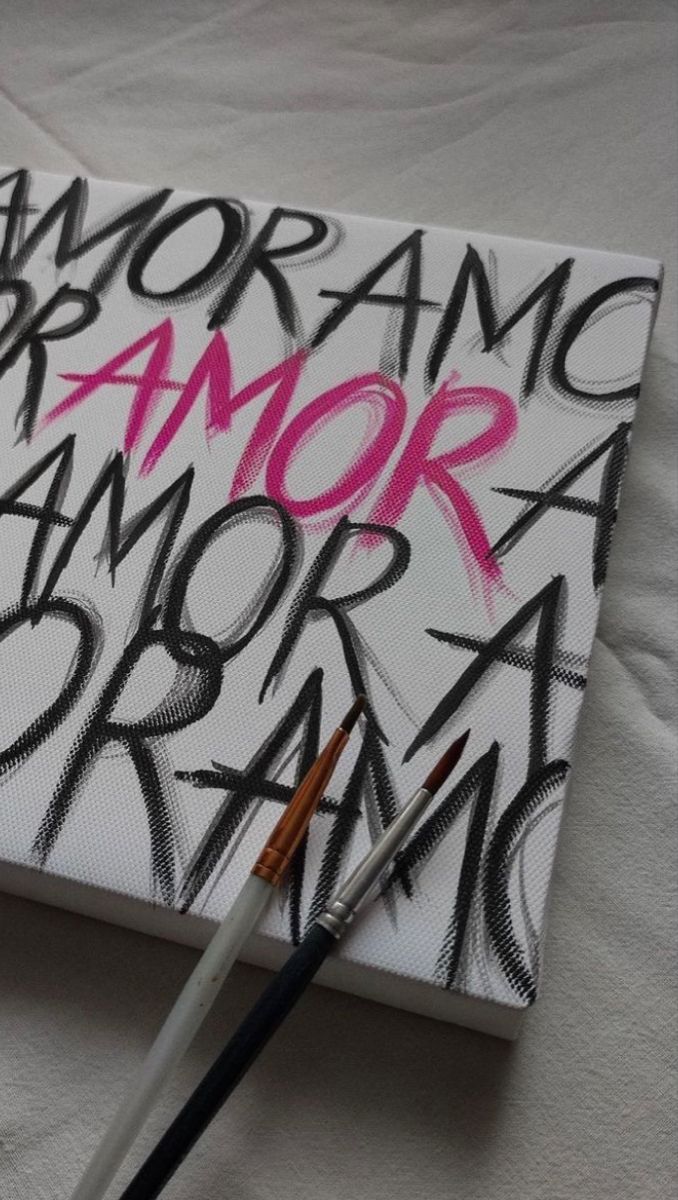 a white canvas with black and pink graffiti on it, next to a paintbrush