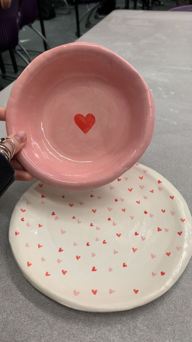 a person holding a pink bowl with hearts on it and another hand reaching for the bowl