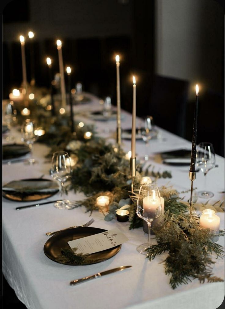 the table is set with candles and greenery