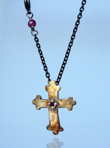 a necklace with a cross on it and a stone bead hanging from the chain