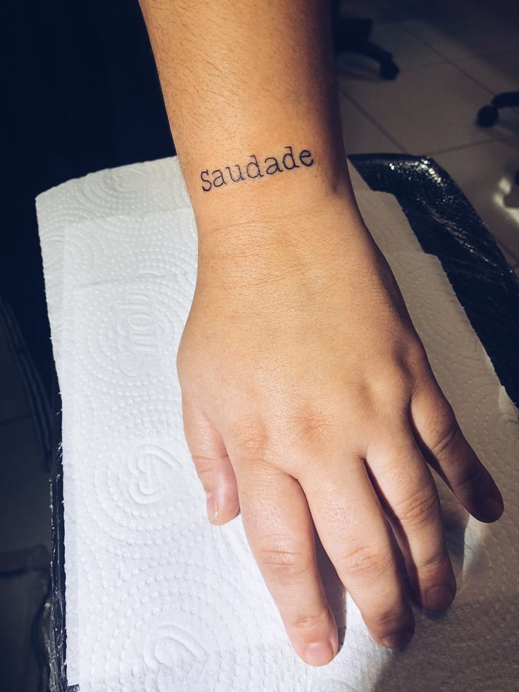 a person with a small tattoo on their wrist that says saunade in cursive writing