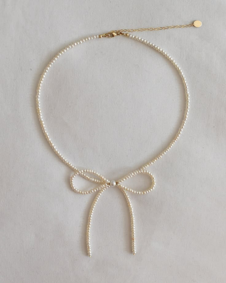 The cutest feminine necklace for your soft girl era. Meticulously handcrafted with care. Model wearing 15" DETAILS. Made with real freshwater AAA grade pearls and 14k gold filled hardware. Lobster clasp with your choice of no extender chain or 1 to 3 inch long extender chain. Bow measures approx. 2.75" wide and 3.25" long. PLEASE NOTE. Freshwater pearls are unique, like you and I. Thus, each jewelry piece is one of a kind and will deviate slightly from the photos shown. Imperfections and small blemishes are also normal. CARE. Avoid direct contact with sunscreen, perfume, hairspray, and skincare products. Jewelry should be the last thing you put on and the first thing you take off. Avoid showering, swimming, exercising, and sleeping with your jewelry on. Clean with a soft cloth after every Pearl And Gold Beads Necklace, Beaded Ribbon Necklace, Coquette Pearl Necklace, Cute Girly Jewelry, Pearl Beaded Jewelry, Diy Chain Jewelry, Bow Necklace Diy, Sunscreen Perfume, Pearl Bow Necklace