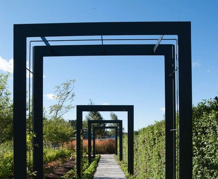 the walkway is lined with black metal structures and plants on both sides, along with blue skies above