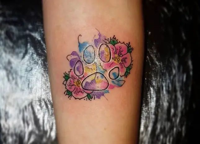 a dog's paw with flowers and hearts tattoo on the left leg, next to a woman's foot