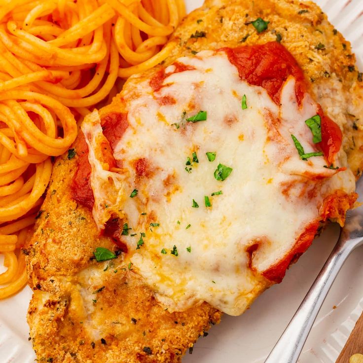 a white plate topped with chicken parmesan and pasta