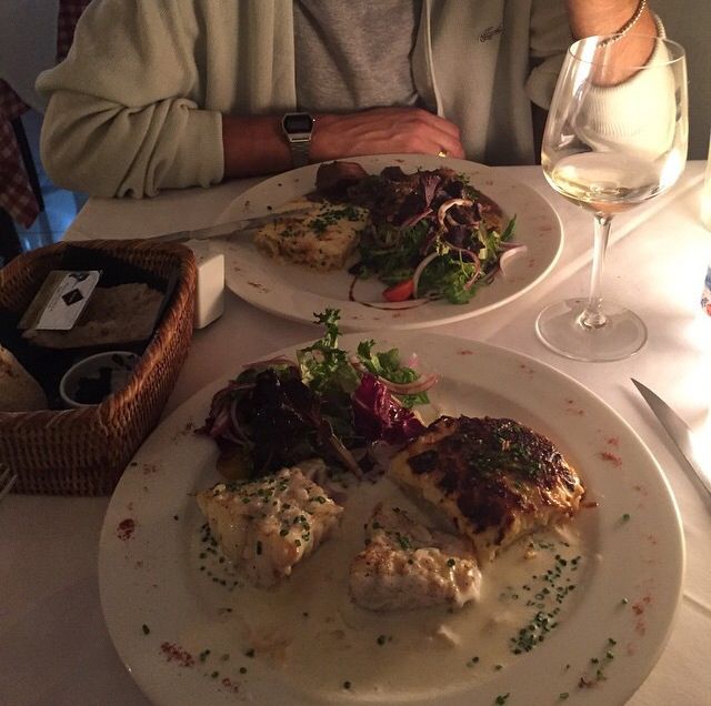 a man sitting at a table in front of two white plates with food on them