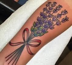 a woman's arm with flowers and a bow tattoo on the left side of her arm