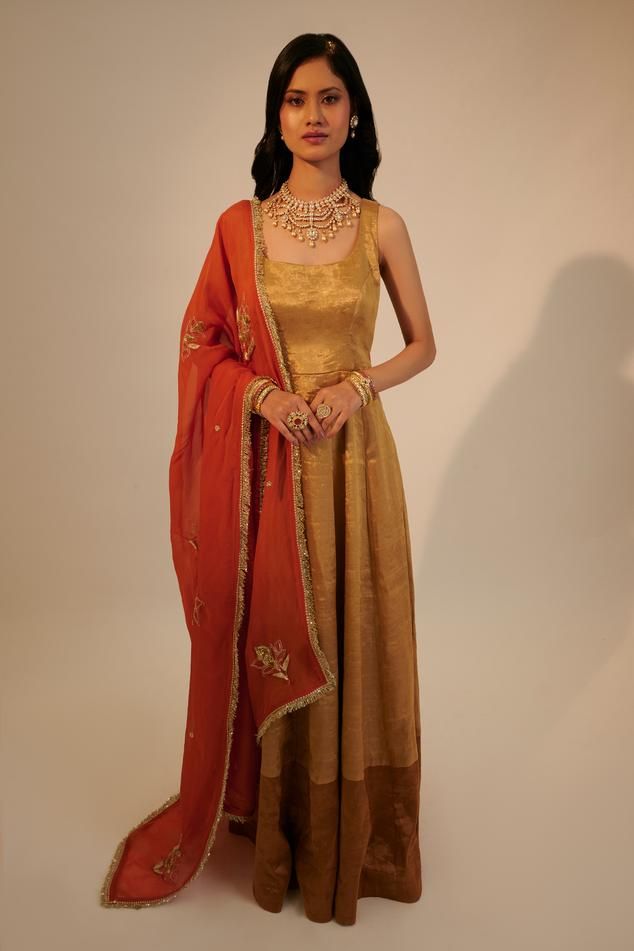 Gold metallic anarkali with square back and dark gold border. Paired with contrast rust dupatta with cut dana, bead, sequin and zari embroidery.
Components: 2
Pattern: Embroidered
Type Of Work: Zari, Sequin, Cut Dana and Bead Work
Neckline: Square Neck
Sleeve Type: Sleeveless
Fabric: Handwoven Tissue, Silk Cotton, Organza
Color: Gold
Other Details: 
Attached lining
Kiran lace dupatta border
Round back
Weight: 3 kgs
Occasion: Mehendi and Haldi - Aza Fashions Anarkali With Dupatta, Dupatta Border, Zari Embroidery, Gold Border, Dark Gold, Anarkali, Aza Fashion, Sleeve Type, Square Neck