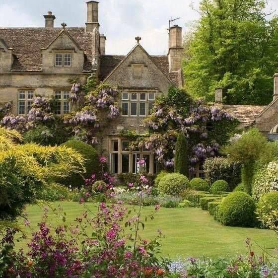 a large house surrounded by lush green trees and flowers