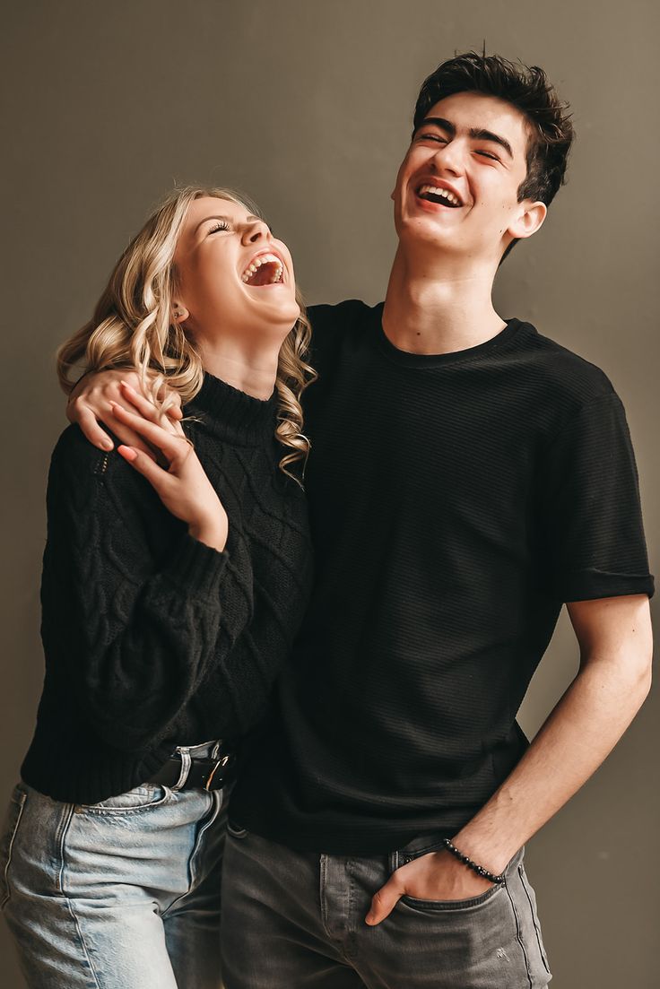 two people standing next to each other and laughing