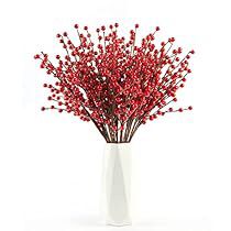 a white vase filled with red berries on top of a table