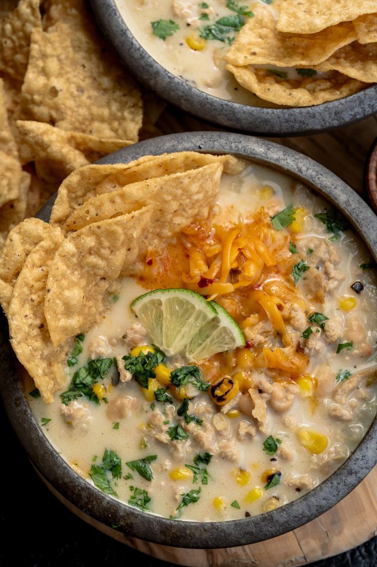 two bowls filled with white chicken chili and tortilla chips