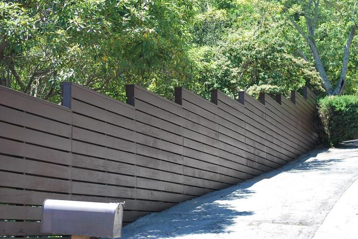 a wooden fence next to a sidewalk and trees