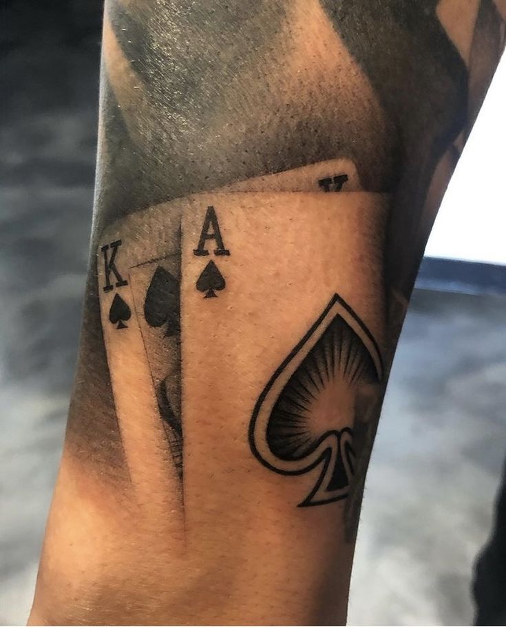 a man's arm with playing cards tattoo on it