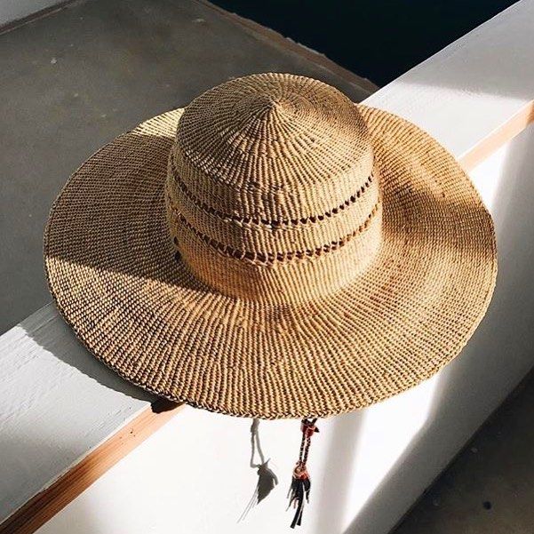 a straw hat sitting on top of a window sill next to a white wall