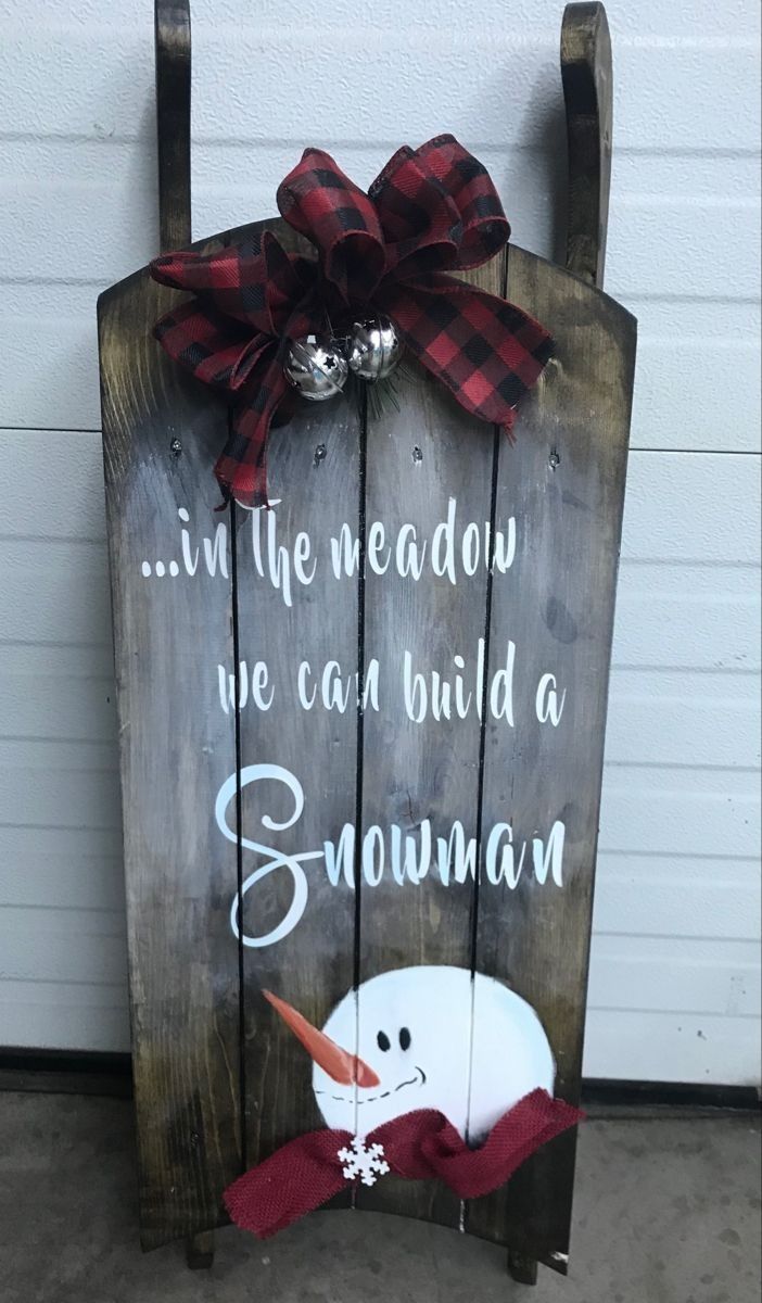 a wooden sign that says, in the meadow we can build a snowman with a red bow