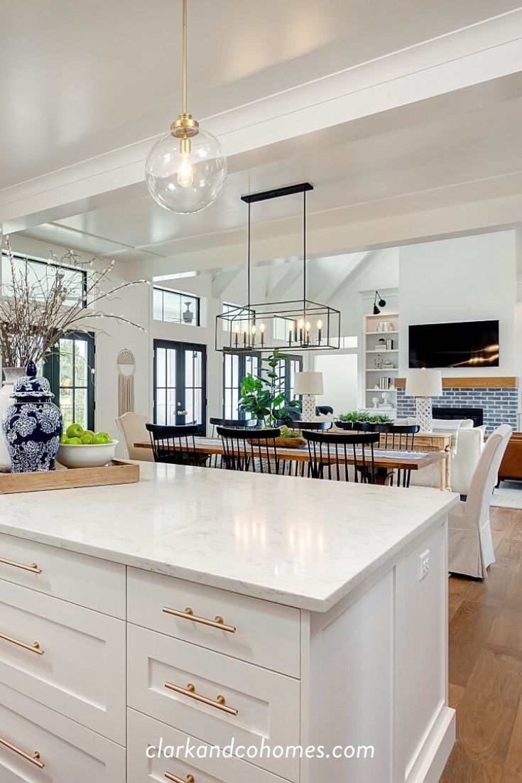 a large kitchen with white cabinets and an island in the center is decorated with blue and white vases