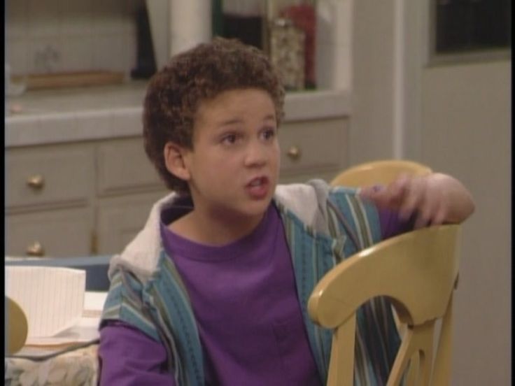 a young boy sitting in a yellow chair with his hand on the back of it