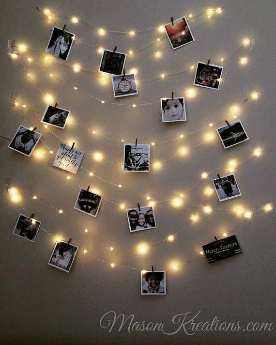 a string of lights with pictures hanging from it's sides and photos pinned to the wall