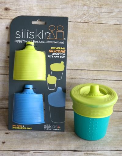 a blue and yellow sippy cup next to a packaging on a wooden table with the lid open