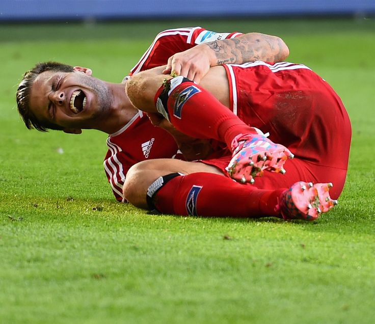 a soccer player laying on the ground with his head in his hands and mouth wide open