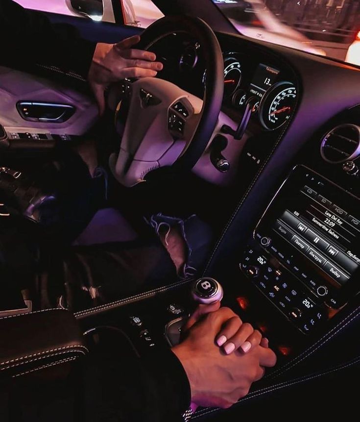 a man sitting in the driver's seat of a car with his hand on the steering wheel